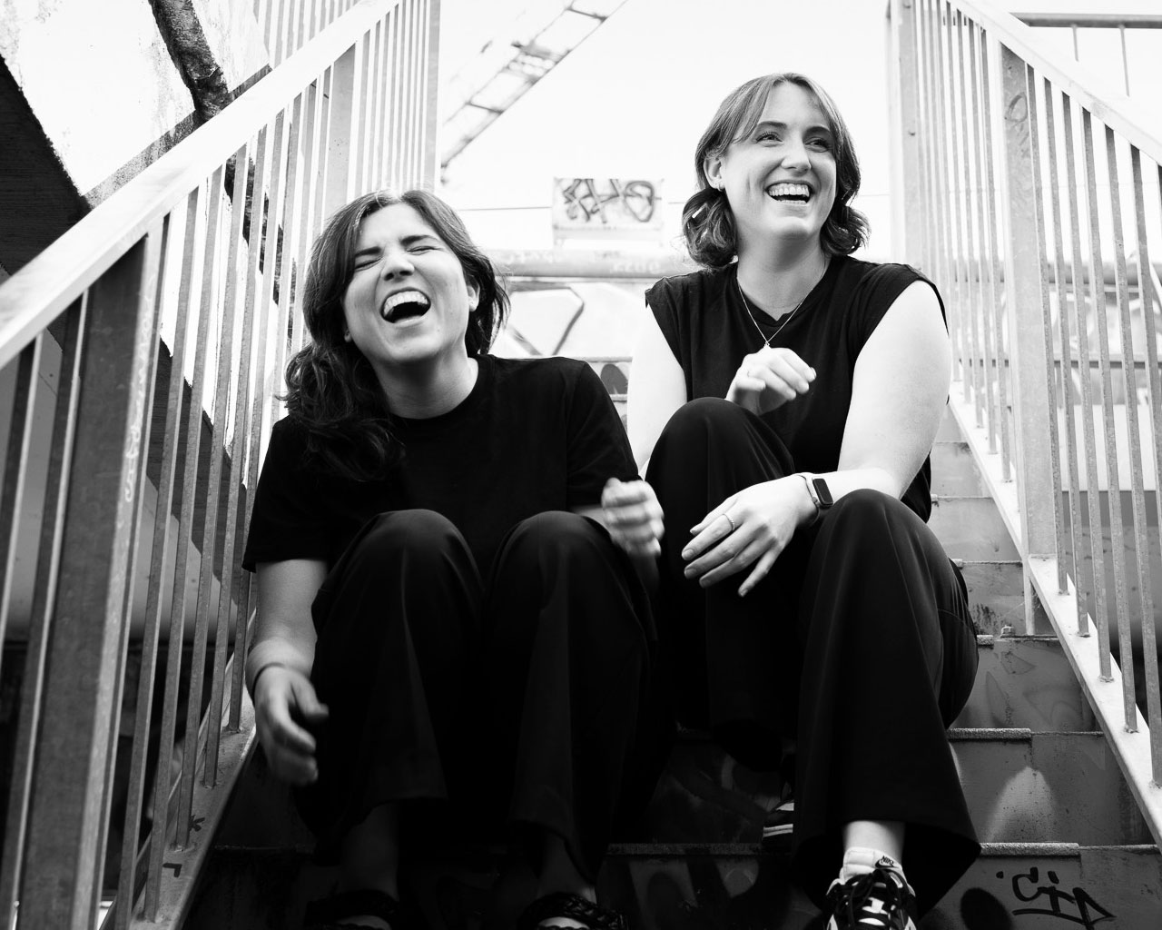 black and white photo of two girls sitting on a stairway.