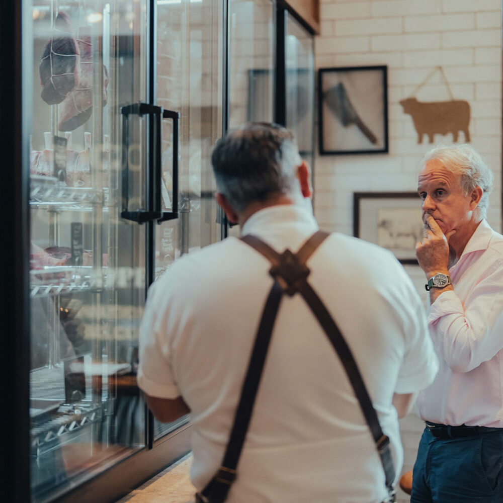 older gentlemen talking inside a butcher shop.